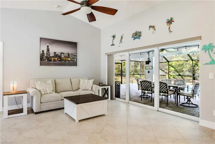 Living room with a sunroom, a ceiling fan, and vaulted ceiling