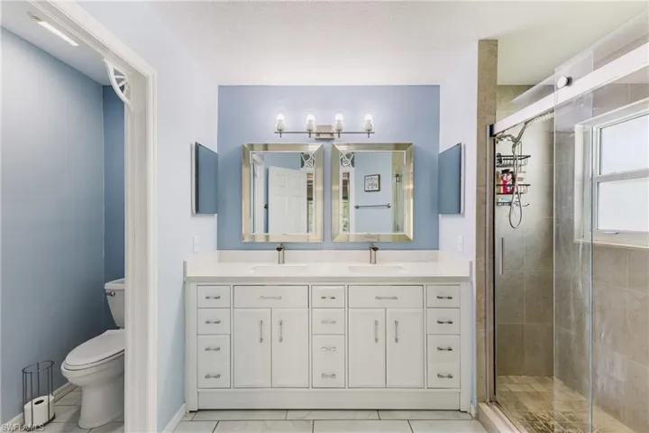 Full bathroom featuring a shower stall, double vanity, and a textured ceiling