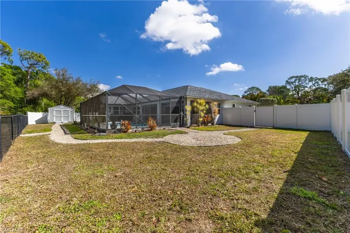 Fenced backyard featuring a storage unit, a sunroom, a lanai, and a swimming pool