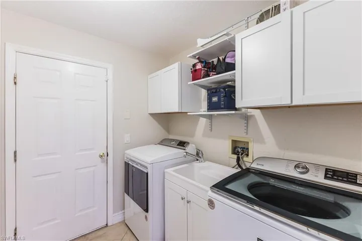 Laundry room with cabinet space, washing machine and dryer, and light tile patterned floors