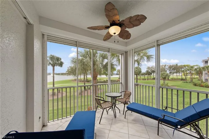 Sunroom / solarium with a textured wall, golf course view, tile patterned flooring, and a textured ceiling