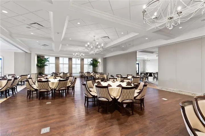Dining room with suspended lighting, dark wood-type flooring, coffered ceiling, a decorative wall, and ornamental molding