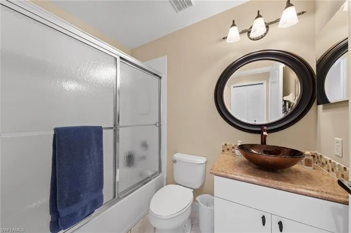 Bathroom with vanity and combined bath / shower with glass door