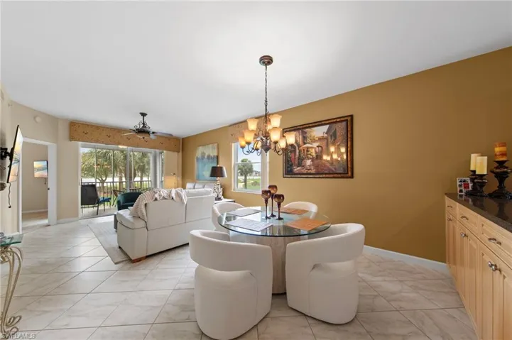 Dining room featuring a ceiling fan, plenty of natural light, a chandelier, and light marble finish floors