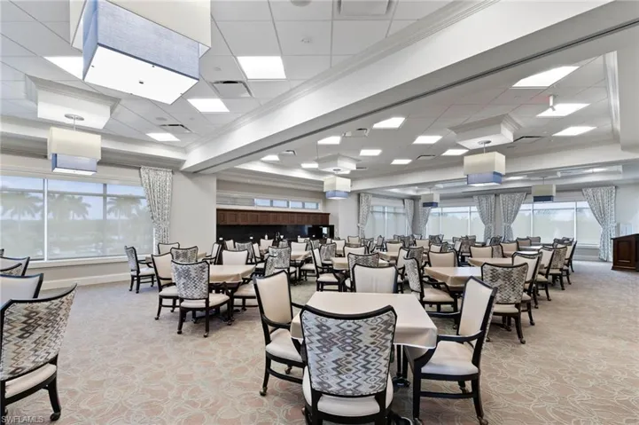 Dining room featuring light carpet, ornamental molding, a drop ceiling, and plenty of natural light