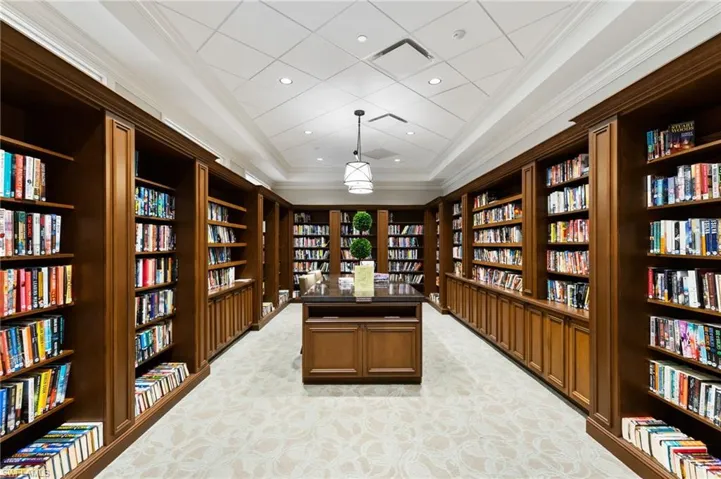 Unfurnished office with wall of books, crown molding, a tray ceiling, and recessed lighting