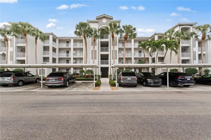 View of apartment building / complex featuring covered parking