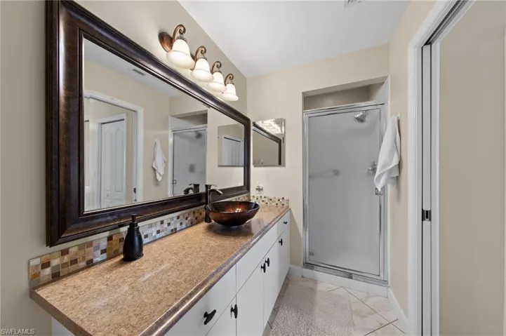 Full bath with vanity, a shower stall, and tasteful backsplash
