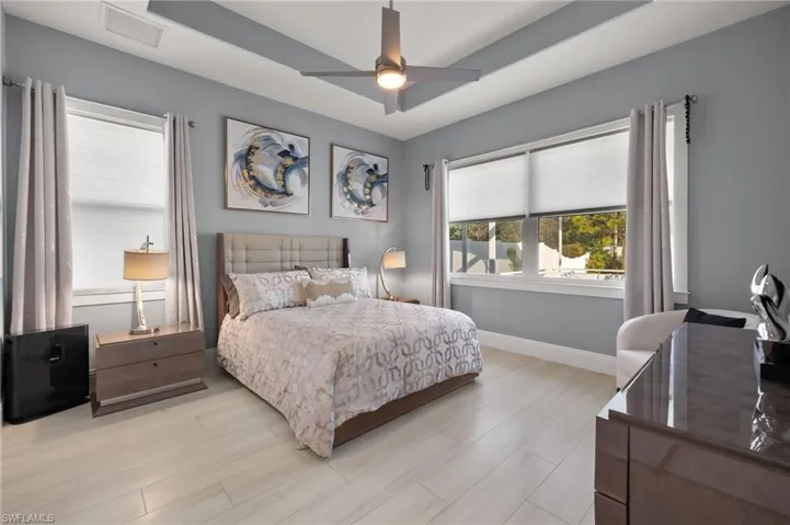 Bedroom featuring a tray ceiling, a ceiling fan, and light wood-type flooring