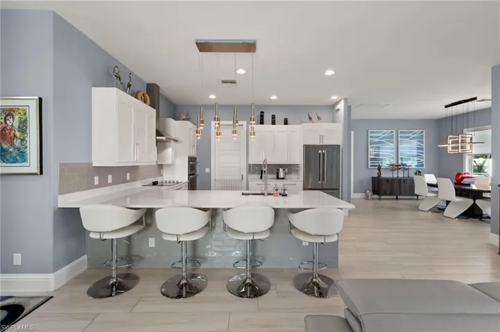 Kitchen with a breakfast bar area, white cabinets, a peninsula, tasteful backsplash, and stainless steel appliances