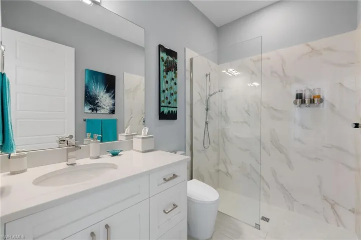 Bathroom featuring vanity and a marble finish shower