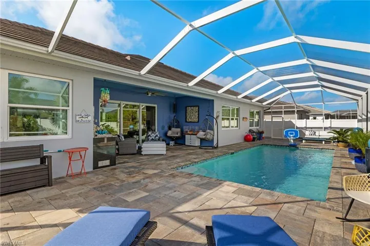 View of swimming pool with a sunroom, patio surround, glass enclosure, and an outdoor living space