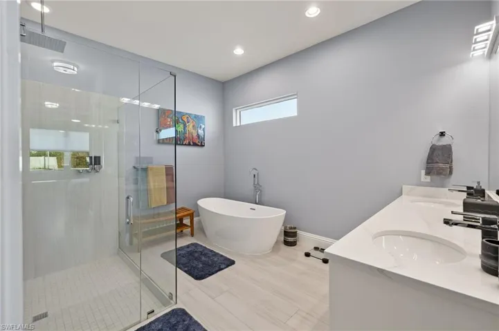 Full bath featuring a stall shower, a freestanding tub, double vanity, and recessed lighting