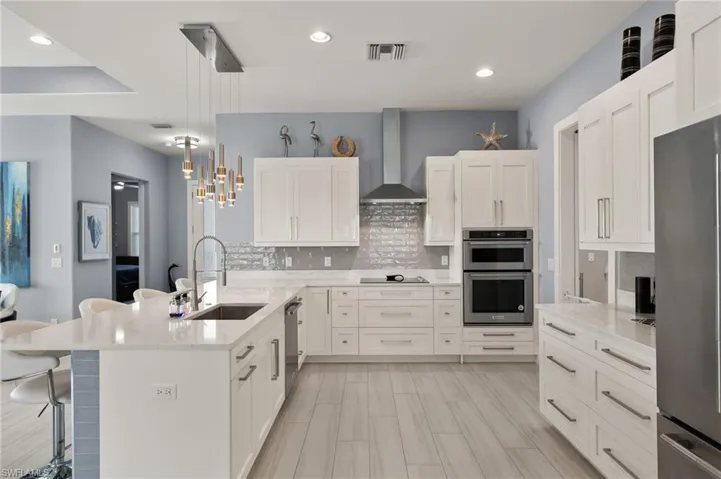 Kitchen with a kitchen breakfast bar, a peninsula, stainless steel appliances, light stone countertops, and white cabinetry