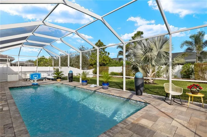 View of pool with a fenced backyard, a sunroom, glass enclosure, and patio surround