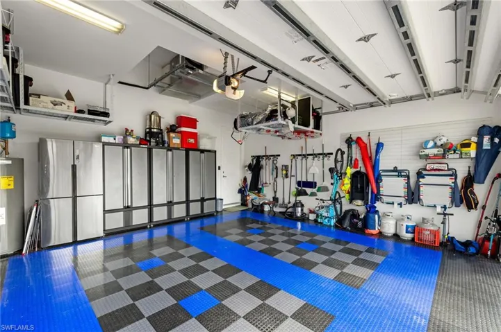 Garage featuring water heater, freestanding refrigerator, and a garage door opener