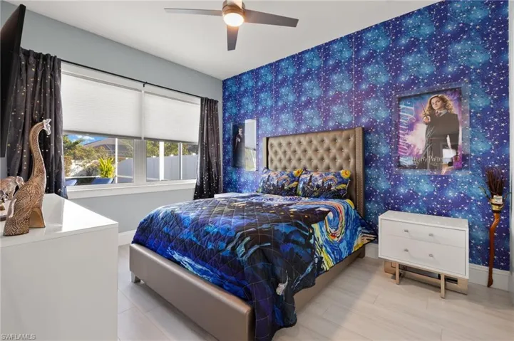 Bedroom with wallpapered walls, ceiling fan, and an accent wall