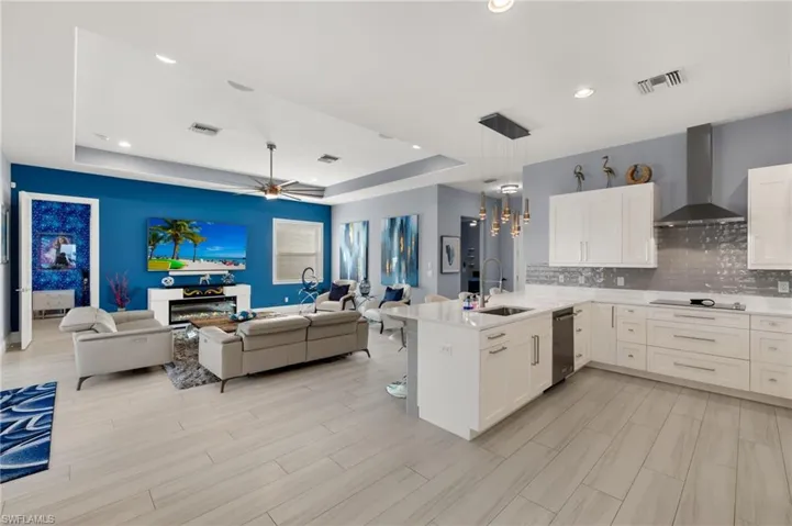 Kitchen featuring a ceiling fan, open floor plan, white cabinetry, a peninsula, and a tray ceiling