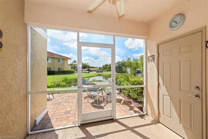 Doorway to outside with a water view, a textured wall, and ceiling fan