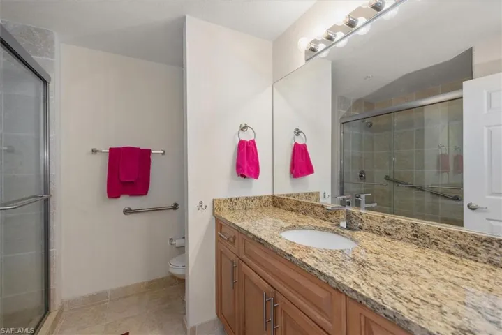 Bathroom with vanity, tiled shower, and light tile patterned flooring