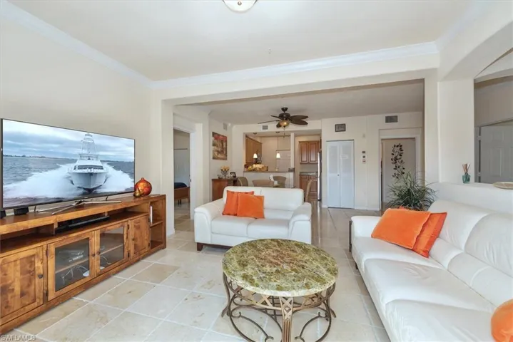 Living room featuring crown molding, ceiling fan, and light tile patterned floors