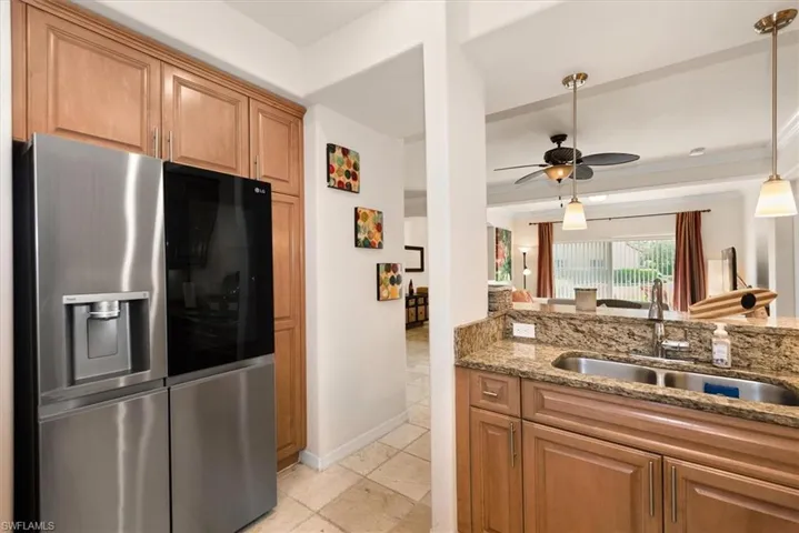 Kitchen featuring stainless steel fridge with ice dispenser, light stone countertops, pendant lighting, and ceiling fan