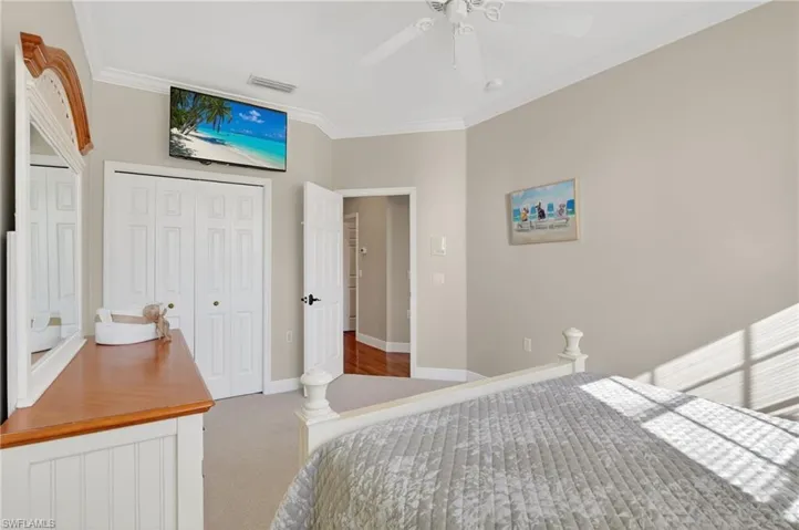 Carpeted bedroom featuring ornamental molding, a closet, and ceiling fan