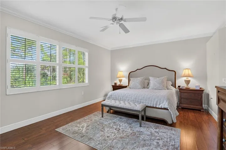 Bedroom with dark wood-style flooring, ornamental molding, and a ceiling fan