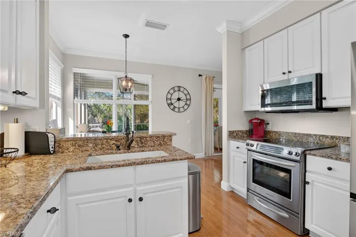 Kitchen featuring white cabinets, stainless steel appliances, and ornamental molding