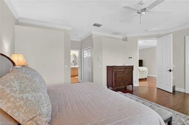 Bedroom with ornamental molding, a closet, hardwood / wood-style floors, a ceiling fan, and connected bathroom