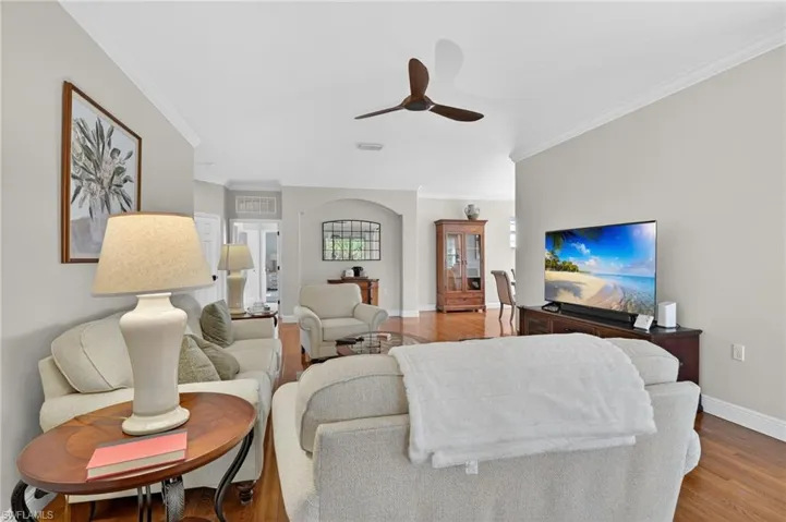 Living area with a ceiling fan, light wood-style flooring, and ornamental molding