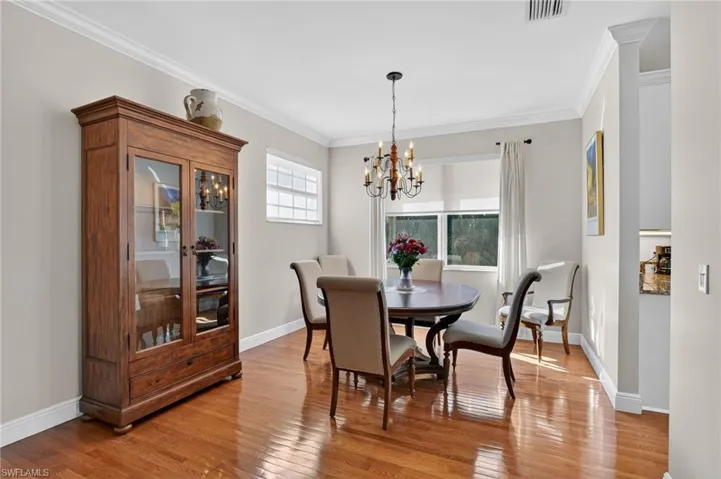 Dining area with light wood-style floors, ornamental molding, and a chandelier