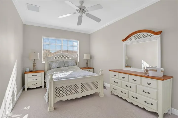 Bedroom featuring ornamental molding, light colored carpet, and a ceiling fan