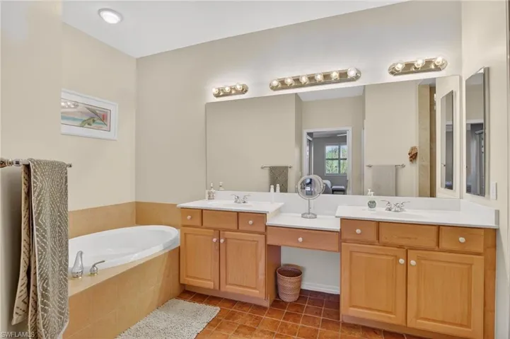 Full bathroom featuring a bath, double vanity, and light tile patterned floors