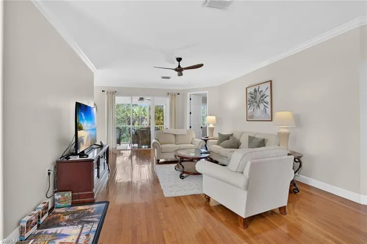 Living area featuring ornamental molding, light wood finished floors, and a ceiling fan