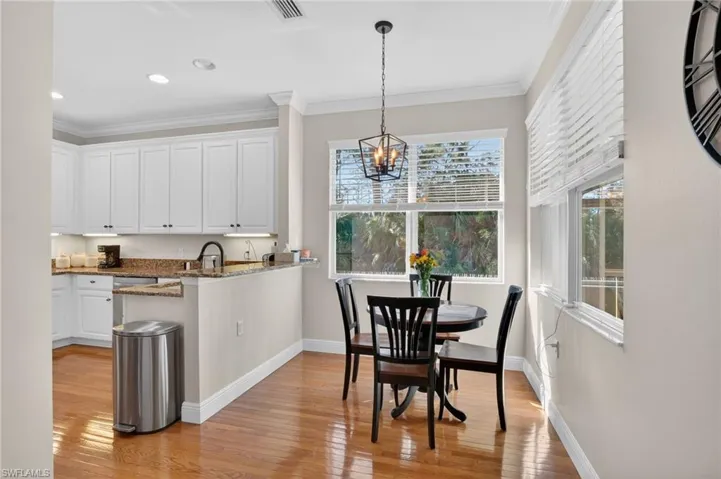 Dining space featuring ornamental molding, light wood-style flooring, hanging lights, and healthy amount of natural light