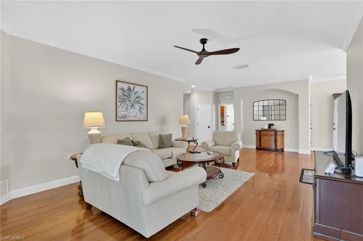 Living area with crown molding, ceiling fan, and light wood-style flooring