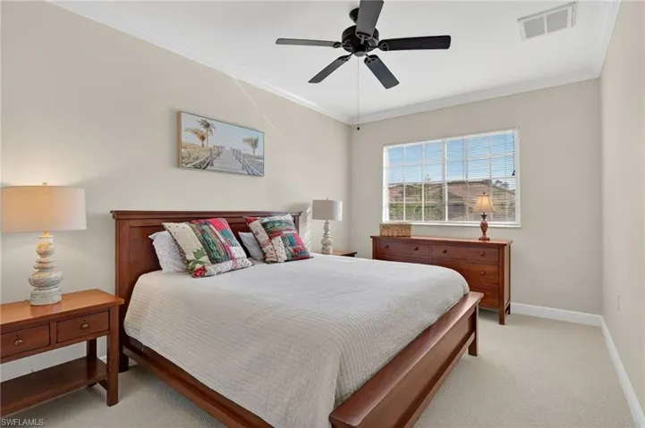 Bedroom featuring light colored carpet, ornamental molding, and ceiling fan