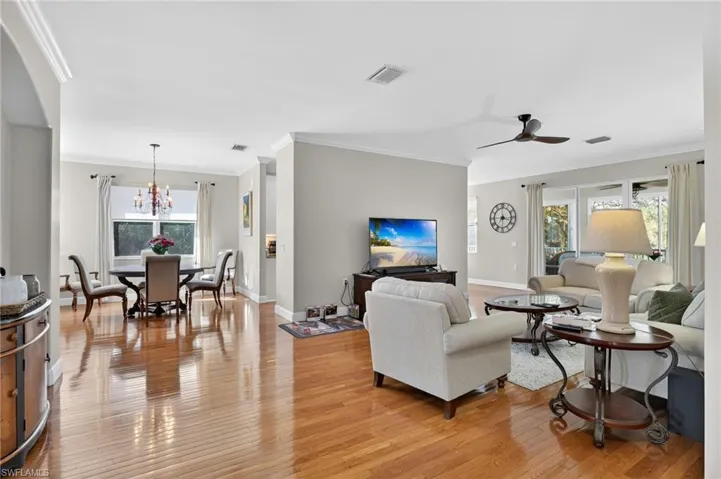 Living room featuring ornamental molding, light wood-style floors, a chandelier, and a ceiling fan