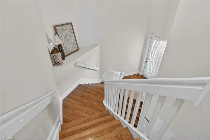 Staircase with wood finished floors and a high ceiling
