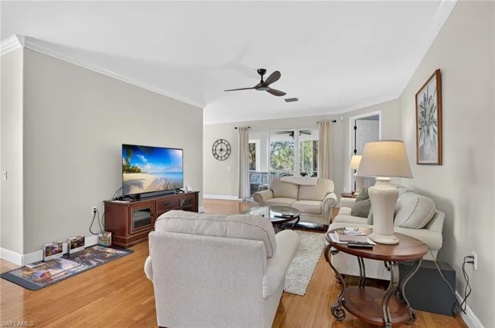Living area featuring light wood-type flooring, ornamental molding, and a ceiling fan