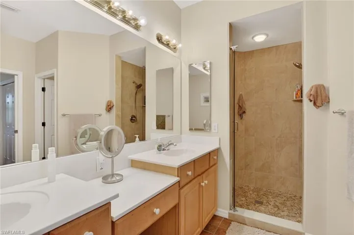 Bathroom with double vanity, a stall shower, and dark tile patterned floors