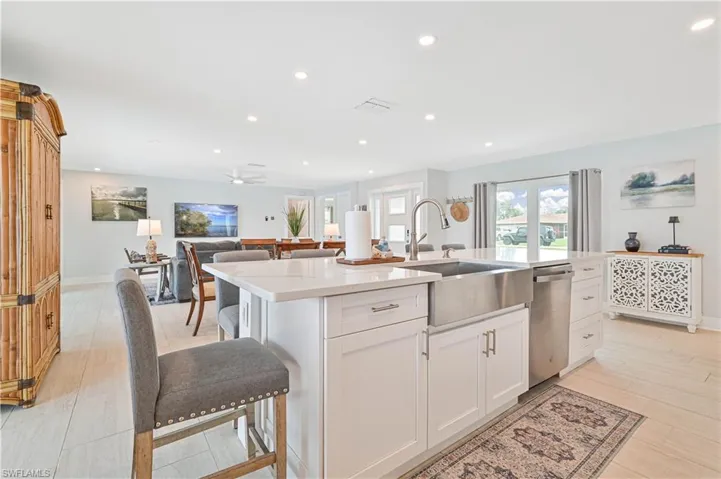 Kitchen featuring dishwasher, a kitchen island with sink, light countertops, white cabinets, and recessed lighting