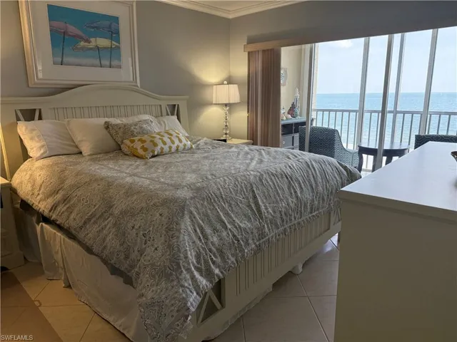 Bedroom featuring a water view, ornamental molding, light tile patterned floors, and access to outside