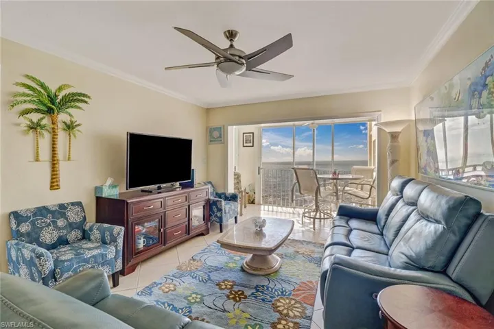 Living area with ceiling fan, crown molding, and light tile patterned flooring