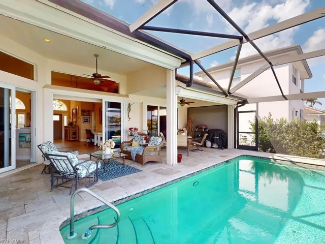 View of pool with a patio, ceiling fan, and glass enclosure