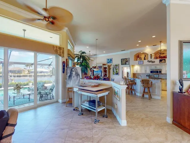 Kitchen featuring ceiling fan, crown molding, a kitchen bar, and hanging light fixtures