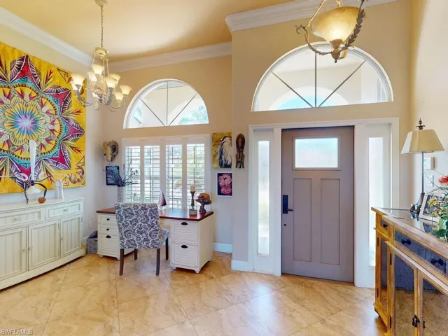 Entryway with ornamental molding, a high ceiling, and an inviting chandelier