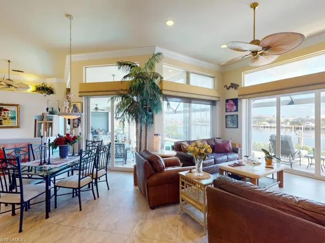 Living room featuring ornamental molding, light tile patterned floors, a water view, and ceiling fan
