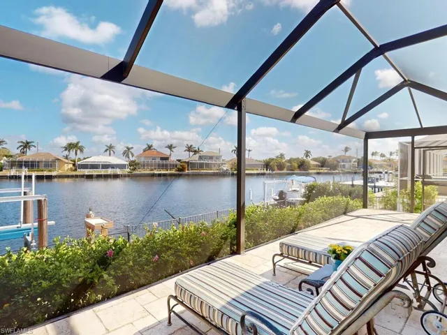 View of patio featuring a dock, a water view, and glass enclosure